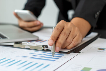 A businessman or accountant is sitting holding a pen to check the company's profit chart, the concept of growth planning in long-term investments.