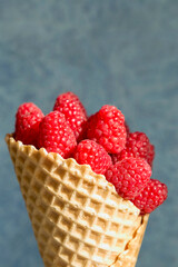 Raspberry dessert in a waffle cone on a dark background.