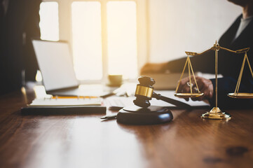 The lawyer works at an office desk. Gavel and scales on the lawyer's desk for justice.