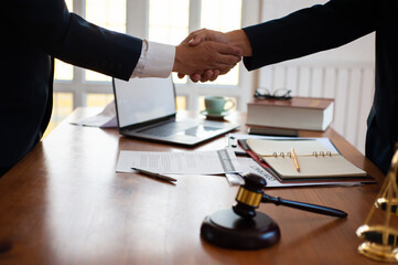 Business people shake hands while signing an agreement in an attorney's office.