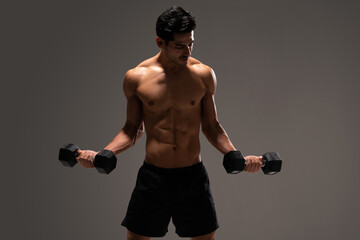 Attractive Male Athlete Exercising Against Gray Background