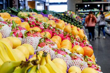 Fruit shop greengrocer display shelf with exotic fruits - mangoes, oranges, dragonfruits, bananas,...