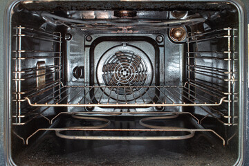 Inside view of a used open dirty stained oven and grilled metal tray