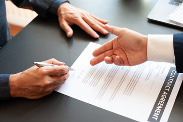 Two businessmen who are negotiating and signing contract agreement documents.