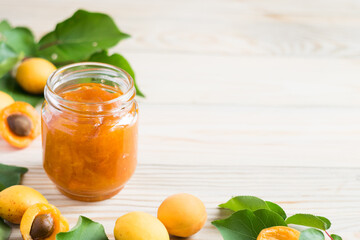Apricot jam in glass jar and ripe apricots on wooden rustic table, selective focus, horizontal orientation, copy space