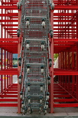 A lot of shopping carts near the shopping mall. Сontemporary art from shopping trolleys. Wooden pallets and red metal frame. Circle from trolley. Crazy shopping and sales time. Selective focus.