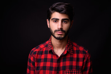 Obraz premium Young handsome bearded Persian man against black background