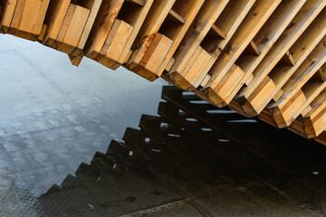 Wooden pallets and reflection in the puddle. Image with selective focus and noise effect.