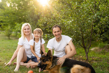 Portrait of an extended family with their pet dog sitting at the park