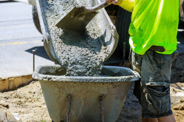 Wheelbarrow with shovel full of cement concrete of concrete mixer truck