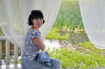 Portrait of a beautiful European woman resting in a gazebo by the lake.