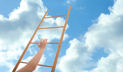 Woman climbing up wooden ladder against blue sky with clouds, closeup. Banner design