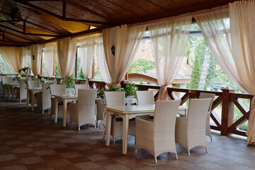 Empty cafe with rattan wicker armchairs and tables on summer garden terrace outdoor, copy space.