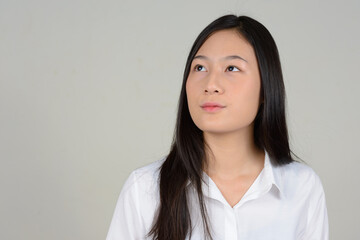 Portrait of young beautiful Asian businesswoman against white background