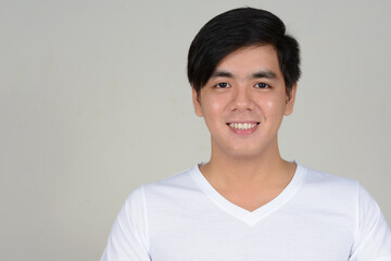 Portrait of young handsome Asian man against white background