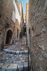 A cobbled street with stairs shows how the lifestyle must have looked like in a medieval village. Narrow, wealthy alley with arch in the historical town centre - Saint Paul de Vence, France