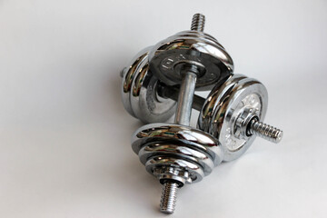 Silver coloured shiny metal dumbbell standing at pile of disks close-up