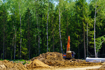 Construction of a new road. Red excavator leveling sand
