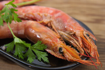 A plate with raw shrimp next to a sprig of parsley