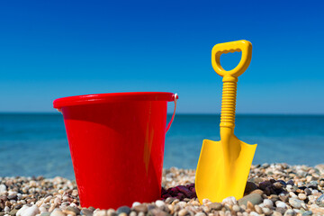 Toy bucket and spade on the beach stones