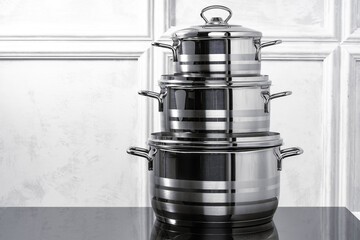 Aluminum cookware on black induction stove against grey wall