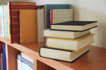 Close-up of several books stacked on the bookshelf in the library selective focus and shallow depth of field