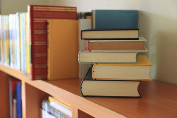 Close-up of several books stacked on the bookshelf in the library selective focus and shallow depth of field
