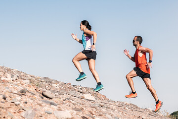 Healthy young couple running on mountain trail.