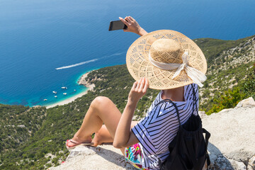 Active sporty woman on summer vacations taking selfie picture while enjoying beautiful coastal view of Cres island, Croatia from Lubenice traditional costal village.