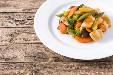 Stir fry chicken with vegetables on wooden table. Copy space