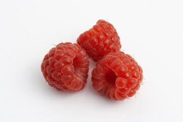 Three ripe raspberries isolated on a white background close-up. Fresh raspberries without sheets on the table. Macro shooting. Healthy and wholesome food concept