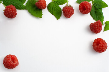 Ripe raspberries isolated on white background close-up. Beautiful red fresh raspberries with leaves along the contour on the table. Top view. Free space for text
