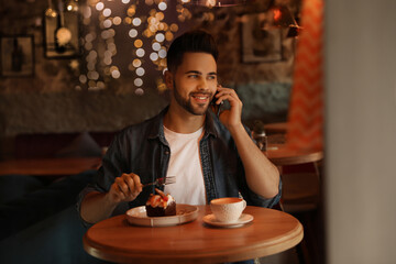 Young blogger talking on phone at table in cafe