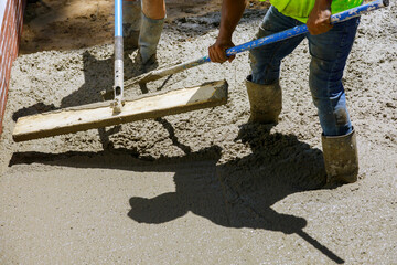 Labour builders at construction site filling formwork with cement workmen in the process forming...