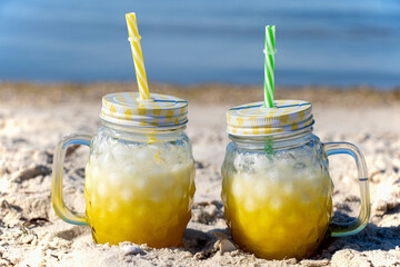 A yellow cocktail in a copper mug stands on the seashore. Sunny day, golden sand and a cooling drink. Yummy.