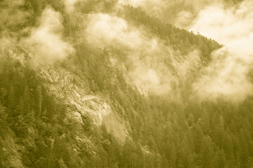 Monochrome sepia vintage style foggy mountain landscape with mist and clouds