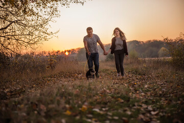 A young man and a girl are walking  in the autumn forest next to the lake. Couple in love  spend...