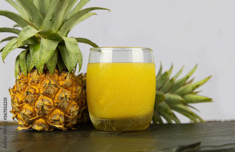 Wall mural a glass of pineapple juice on black stone table background.