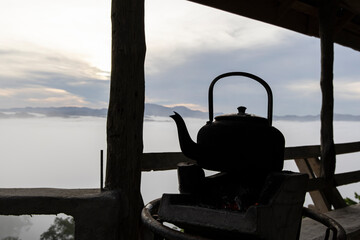 Close up of old kettle with charcoal stove and fog on the mountain background in the morning.