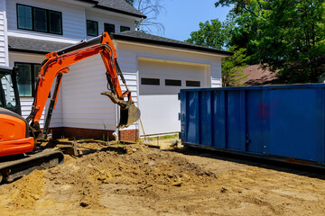 Mini excavator on construction site for working in trash container construction dumpsters