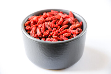 Goji berries in a bowl on white background