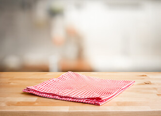 Red fabric,cloth on wood table top on blur kitchen counter (room)background