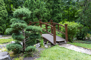 Landscaped park with green trees and an asian style bridge.