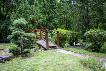 Landscaped park with green trees and an asian style bridge.