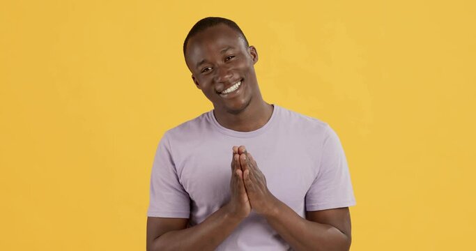 Grateful black man clasping hands and smiling