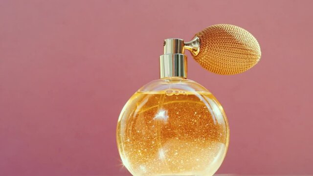 Luxury golden perfume bottle and shining light flares on pink background, glamorous fragrance scent as perfumery product for cosmetic and beauty brand, stock footage