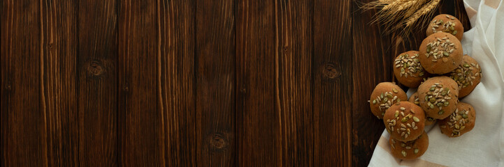 Banner 3:1. Fresh homemade crispy bread buns with bran, sunflower and pumpkin seeds on brown wooden background. Top view.