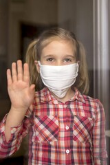 Portrait of an adorable female child wearing a protective medical face mask and waving