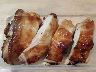 A slice of healthy grilled fresh chicken pork breast serving on plastic tray on wooden table, homemade restaurant, menu advertisement, food stylist backgrounds