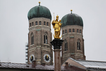 Golden scuplture of Virgin Mary at  Marienplatz with Both onion domes of the Gothic cathedral backgrounds, Munich, Germany, Travel Destinations